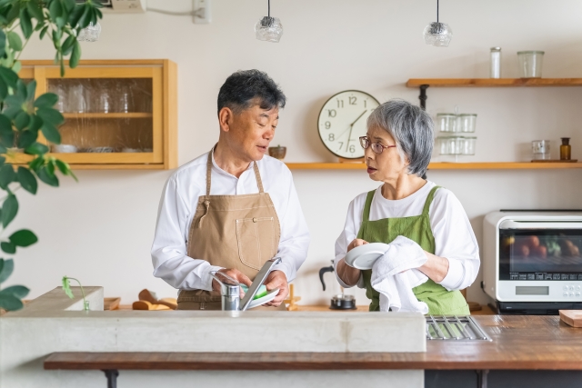 キッチンで皿拭きをする老夫婦の画像